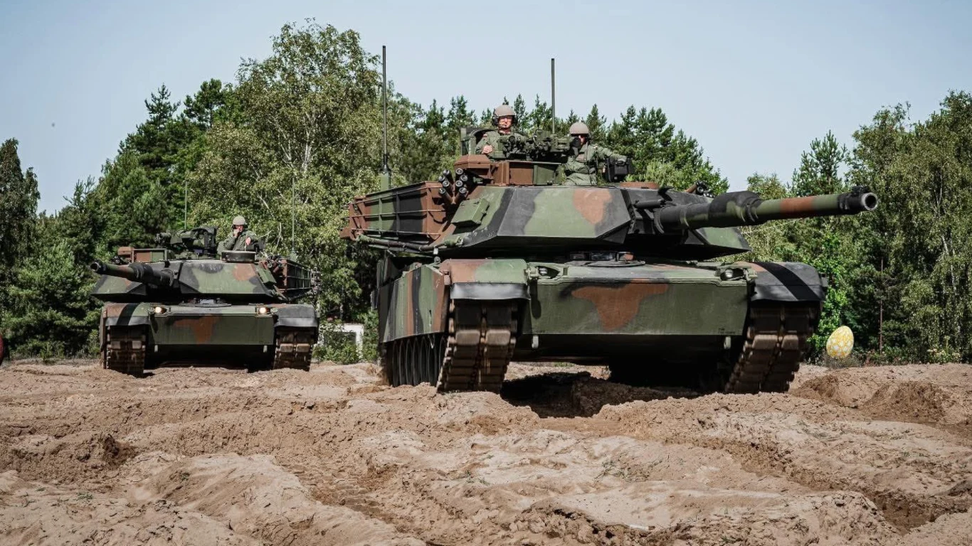 Część czołgów M1A2 Abrams SEPv3 zostanie przekazanych do Centrum Szkolenia Wojsk Lądowych w Poznaniu, zastępując tam czołgi wypożyczone od armii USA Dwa czołgi w kamuflażu leśnym poruszające się po piaszczystym terenie, w tle drzewa i krzewy. Załoga w hełmach widoczna na pancerzu czołgów.