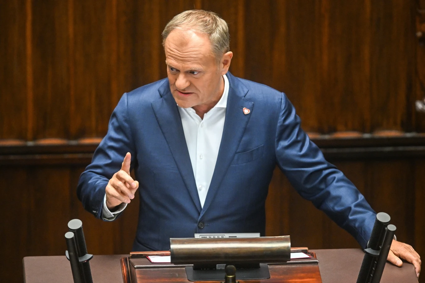 Przemówienie Donalda Tuska w Sejmie Mężczyzna w garniturze przemawia przy mównicy, używając gestów ręką. W tle drewniana aranżacja sali.