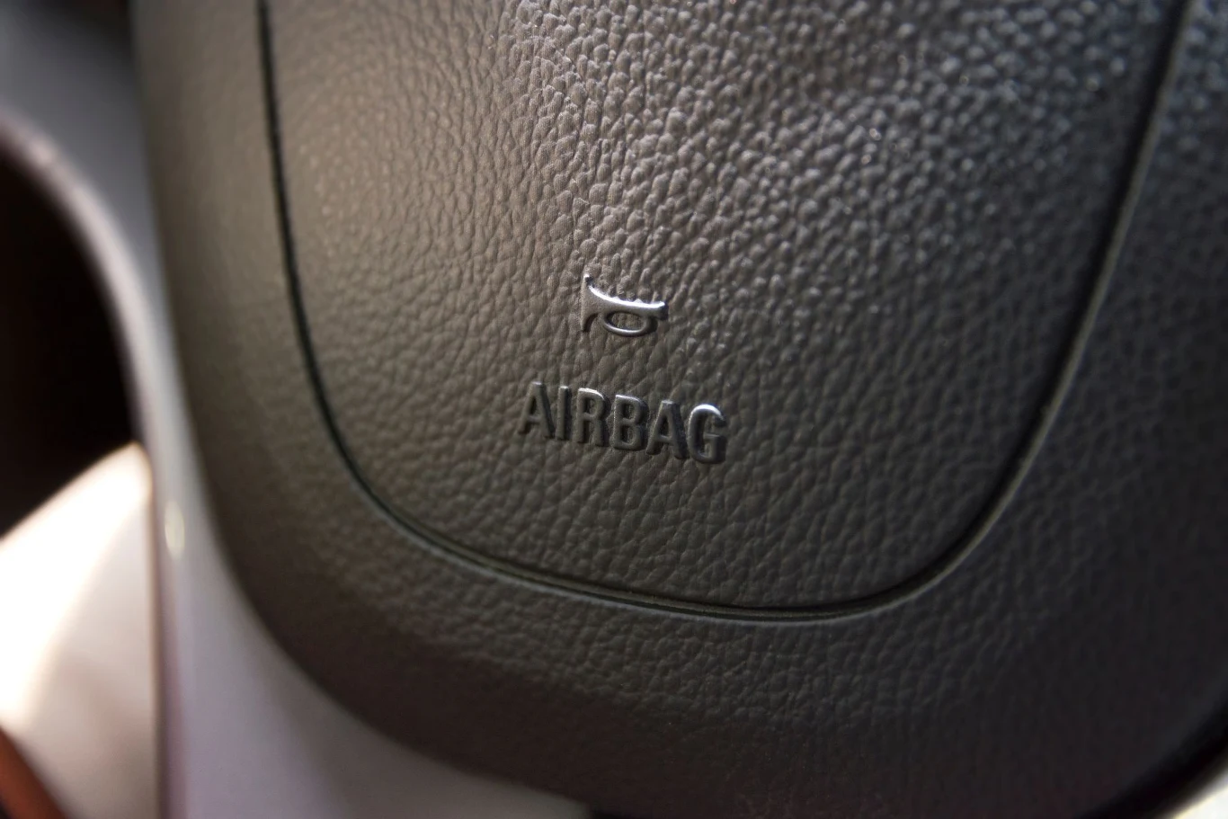 Zbliżenie na kierownicę samochodu z wyraźnym napisem 'AIRBAG' oraz symbolem poduszki powietrznej.