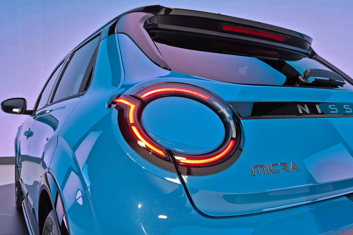 Niebo kolorowe, tył niebieskiego samochodu Nissan Micra, nowoczesne oświetlenie tylnych lamp.