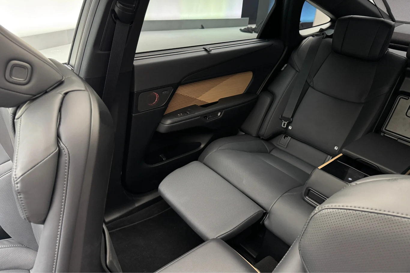 Nie tylko kierowca cieszy się wyjątkowym komfortem. Pasażer może poczuć się niczym VIP. Wnętrze luksusowego samochodu z widocznymi tylnymi siedzeniami wykończonymi skórzaną tapicerką, rozkładanym podnóżkiem, eleganckimi przeszyciami oraz elementami drewnianymi na boczkach drzwi.