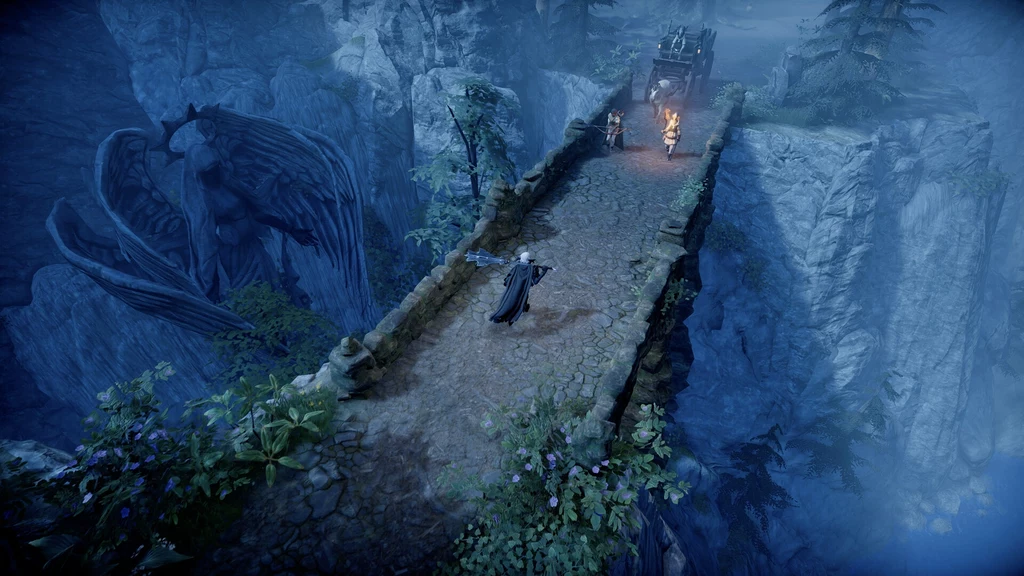 V Rising - screen z gry Kamienny most zawieszony nad głębokim wąwozem, po którym idzie postać w ciemnym płaszczu, a na jego końcu stoją dwie osoby z pochodniami i wóz. Po lewej stronie skała z rzeźbioną sylwetką anioła lub gargulca, otoczona mgłą i gęstymi roślinami.