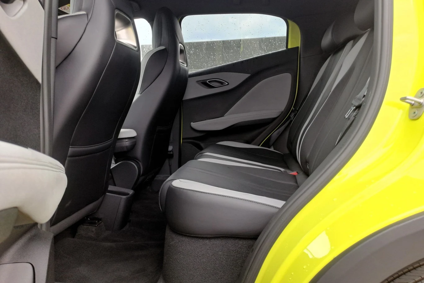 Tylny rząd siedzeń samochodu osobowego, tapicerka dwukolorowa, widoczne czarne oraz szare elementy wnętrza, drzwi i przednie fotele w nowoczesnym stylu.