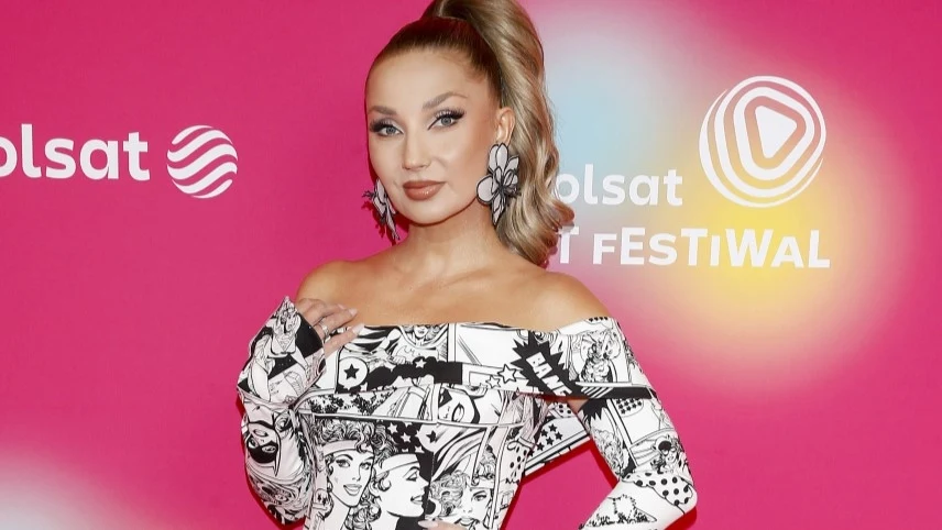 Cleo otworzy Polsat Hit Festiwal Kobieta w oryginalnej, czarno-białej sukience z komiksowym wzorem pozuje na tle różowej ścianki z logotypami festiwalu i telewizji Polsat, ma spięte blond włosy i charakterystyczne kolczyki.