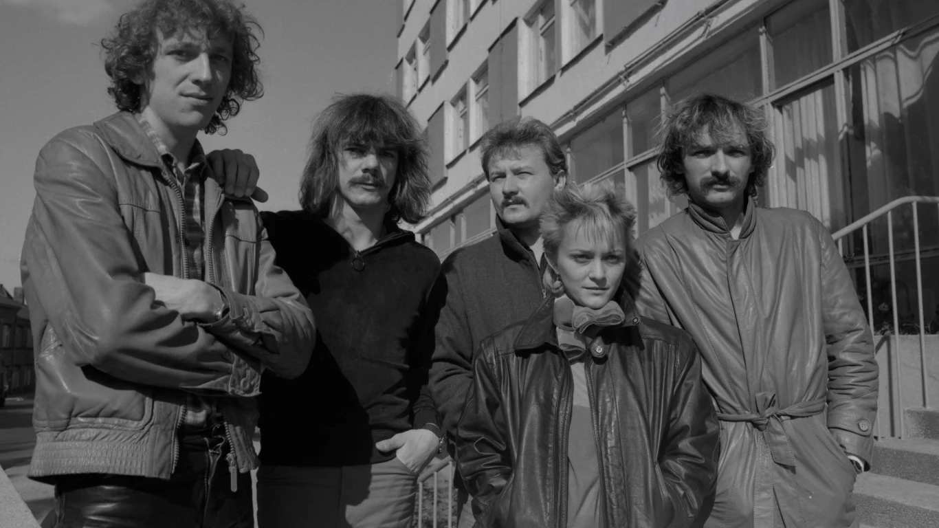 Lombard i Małgorzata Ostrowska Pięć osób w skórzanych kurtkach stoi wspólnie na tle budynku mieszkalnego, tworząc zwartą grupę, klimatem nawiązującą do lat 80. lub 90. wszyscy patrzą w stronę obiektywu, a po prawej stronie widać krawędź schodów.