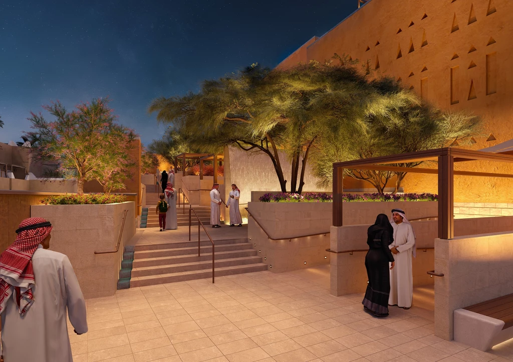Dziedziniec muzeum Asaan inspirowany architekturą Nadżdu Grupa osób w tradycyjnych arabskich strojach rozmawia i spaceruje w elegancko oświetlonym, nowoczesnym otoczeniu z drzewami i geometryczną architekturą, otoczona jasnymi murami i bujną roślinnością.
