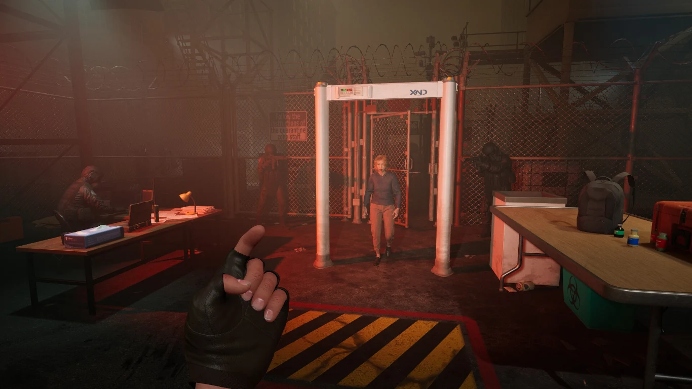 Quarantine Zone: The Last Check Postać przechodzi przez bramkę wykrywającą metal na tle ogrodzenia z drutem kolczastym, po bokach siedzą osoby przy biurkach, przy wejściu pilnuje kilku uzbrojonych strażników, a cały teren jest słabo oświetlony i sprawia wrażenie kontrolowanego.