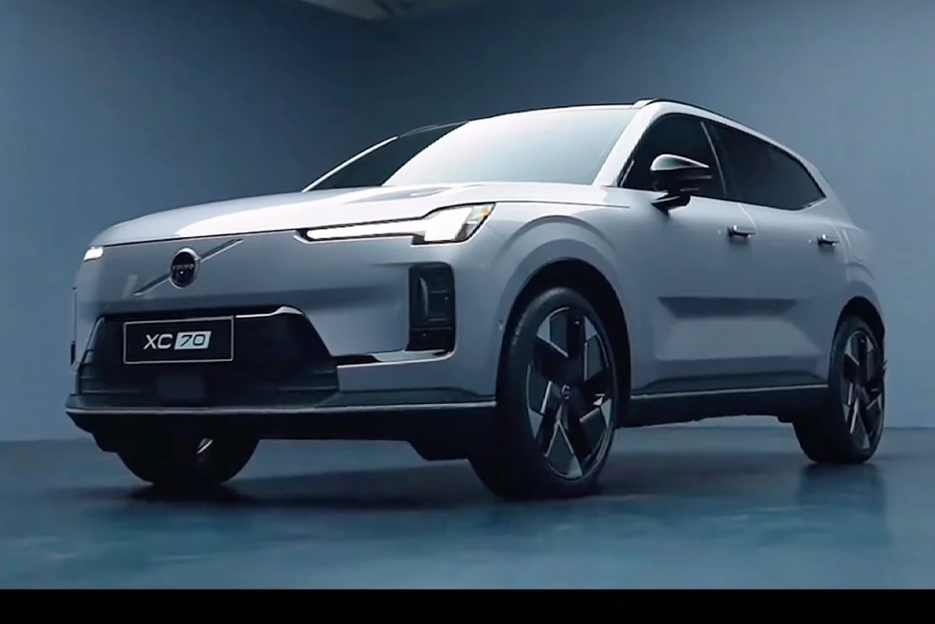 Volvo zaprezentowało nowe XC70 w wersji PHEV Srebrny SUV Volvo XC70 ustawiony w minimalistycznym, jasno oświetlonym studiu na jednolitym niebieskim tle, pojazd zwrócony lekko przodem w lewo, podkreślone nowoczesne linie nadwozia i charakterystyczne światła LED.