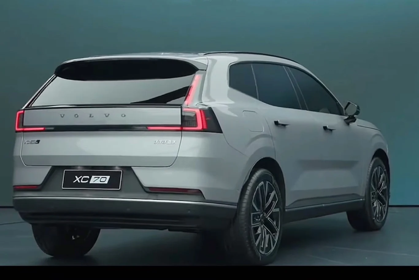 Patrząc na auto od tyłu nikt nie będzie miał wątpliwości, że ma do czynienia z Volvo Srebrny samochód Volvo XC70 ustawiony na tle jednolitej ściany, widok z tyłu ukazujący charakterystyczne tylne światła LED, sportowe felgi i nowoczesną linię nadwozia.