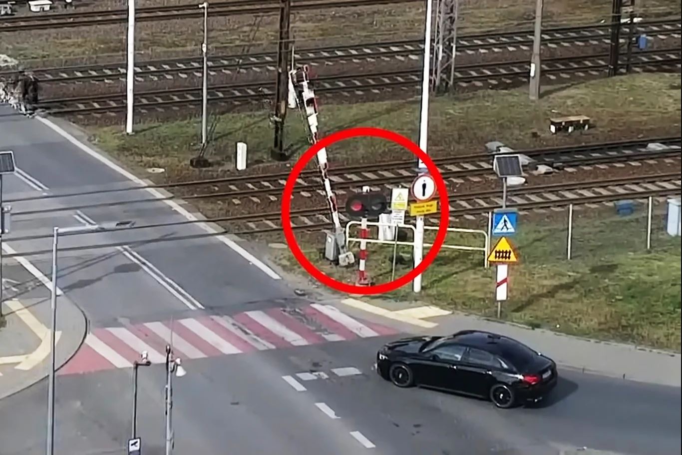 Policjanci skorzystali z tajnej broni. Kierowcy wpadali jeden za drugim | Fot. KMP Bydgoszcz @YouTube Otwarte szlabany na przejeździe kolejowym przy włączonym sygnale czerwonym, samochód zbliżający się do przejazdu oraz widoczne pasy dla pieszych i znaki drogowe.