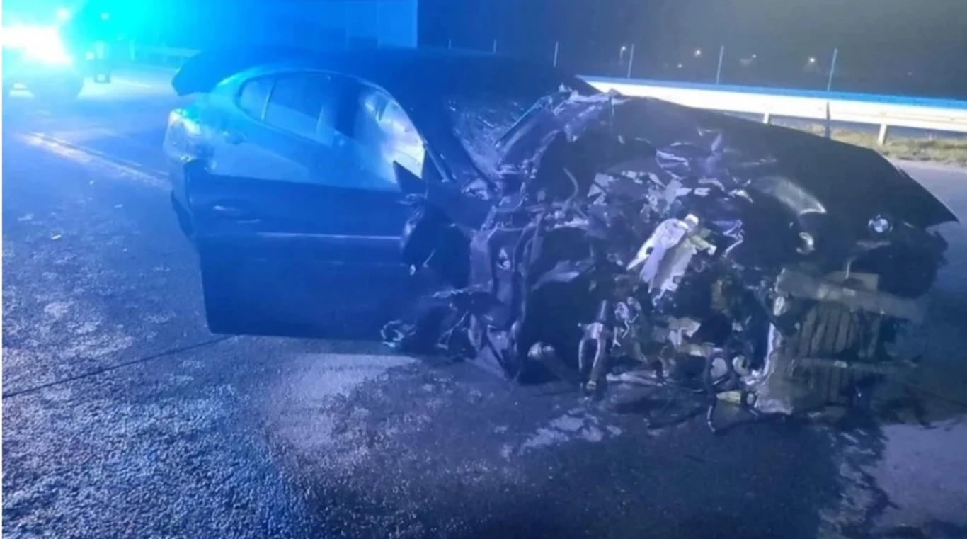 Tragiczny wypadek na A1. Sebastian M. jest konwojowany do Polski przez policję Poważnie zniszczony samochód osobowy stoi na jezdni nocą, przód pojazdu jest doszczętnie zgnieciony, wokół widoczne ślady kolizji oraz światła służb ratunkowych w tle.