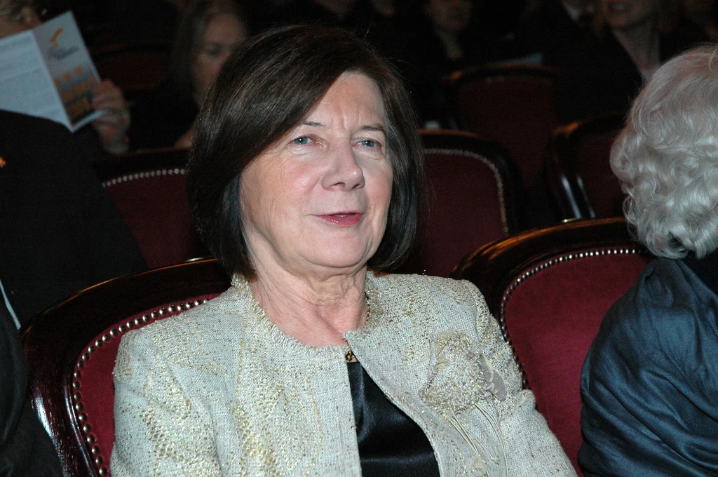 Maria Kaczyńska na uroczystej inauguracji roku Zbigniewa Herberta w Teatrze Narodowym 18 lutego 2008 roku Starsza kobieta w eleganckiej jasnej marynarce siedzi na czerwonym fotelu w teatrze lub sali koncertowej, wokół niej inni widzowie.