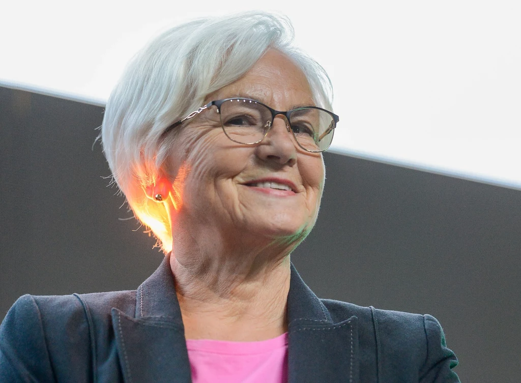 Danuta Wałęsa 20.10.2024 w Łodzi na Igrzyskach Wolności. Starsza kobieta o siwych włosach i okularach, uśmiechnięta, ubrana w różową bluzkę i ciemną marynarkę, na jasnym tle.