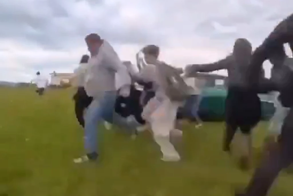 Skrin z filmu opublikowanego przez serwis Remiza. BMW uderzyło już w pierwszych widzów, pozostali próbują uciekać, ale jest już na to za późno Grupa ludzi w różnym wieku biegnie szybko po trawiastym terenie, niektórzy wyciągają ręce do przodu, a wokół panuje lekki chaos, co może sugerować spontaniczne wydarzenie lub zabawę na świeżym powietrzu.