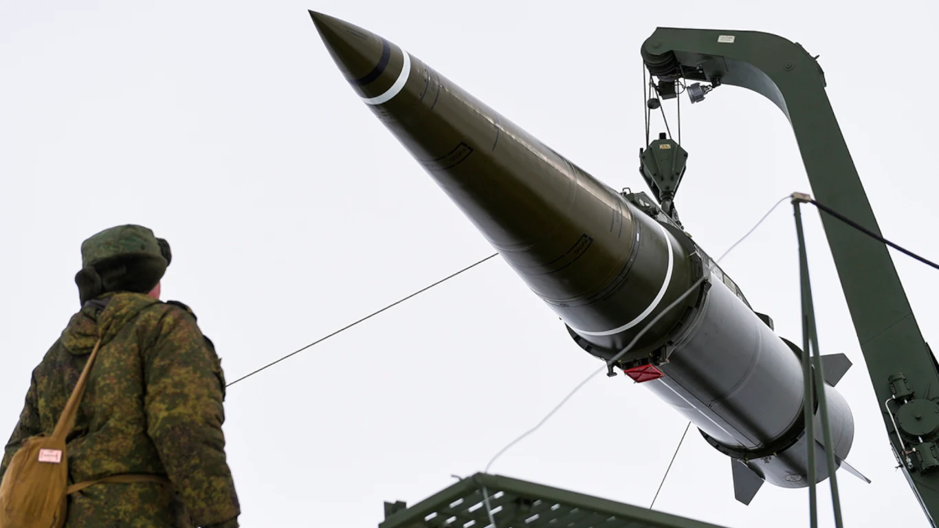 Ukraiński pułkownik: Rosjanie ulepszyli swoje rakiety i trudno je zestrzelić. Eksperci komentują Duży pocisk balistyczny podnoszony przez dźwig, żołnierz w mundurze stoi obok rakiety, tło stanowi jasne niebo.