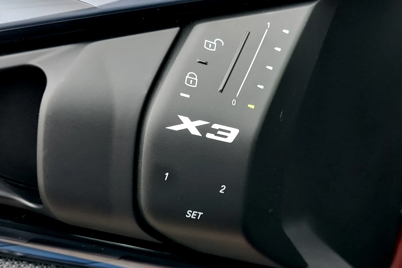 Panel sterowania z przyciskami do ustawienia pozycji fotela kierowcy w samochodzie marki BMW X3, wyraźnie widoczne ikony blokady, pamięci ustawień oraz wskaźniki wyboru ustawienia