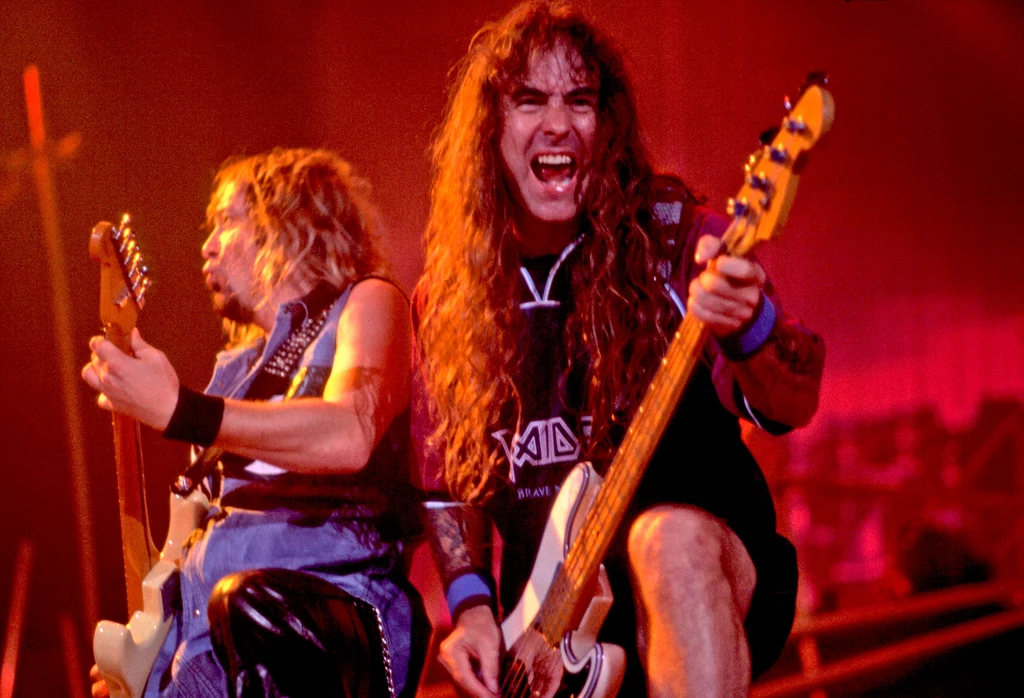 Adrian Smith i Steve Harris (Iron Maiden) w akcji - Chicago, 17 października 2000 r. Dwóch energicznych muzyków grających na gitarze elektrycznej i gitarze basowej na scenie rockowego koncertu, ciepłe oświetlenie podkreśla intensywność występu, a jeden z muzyków wyraża emocje krzycząc do publiczności.