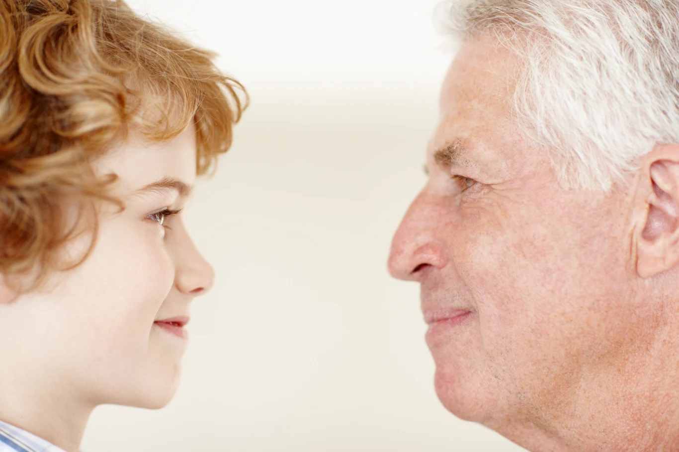 Nowa metoda przywoływania dziecięcych wspomnień Uśmiechnięte twarze starszego mężczyzny z siwymi włosami i dziecka z jasnymi lokami zwrócone ku sobie, wyrażające radość oraz bliskość międzypokoleniową.