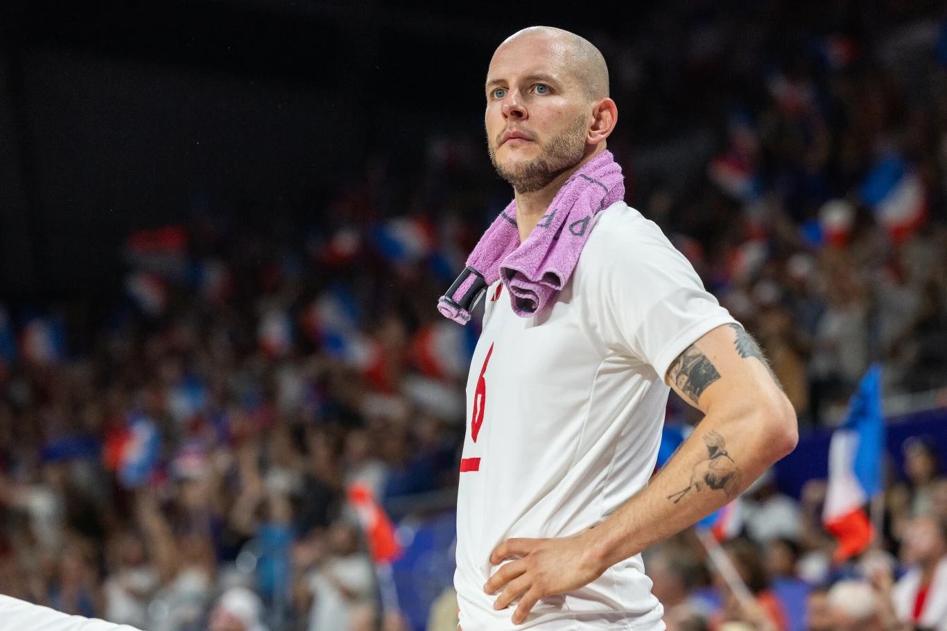 Bartosz Kurek Bartosz Kurek stoi z rękami na biodrach, z ręcznikiem na ramionach, w tle tłum kibiców z flagami