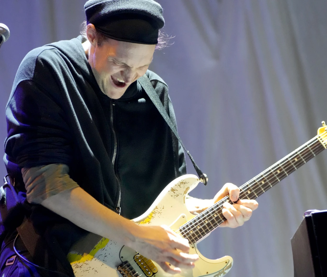 Josh Klinghoffer został uznany winnym spowodowania wypadku ze skutkiem śmiertelnym Muzyk ubrany na czarno gra na elektrycznej gitarze z wyraźnymi oznakami zużycia, wyrażając emocje poprzez intensywny wyraz twarzy, w tle jasna zasłona.