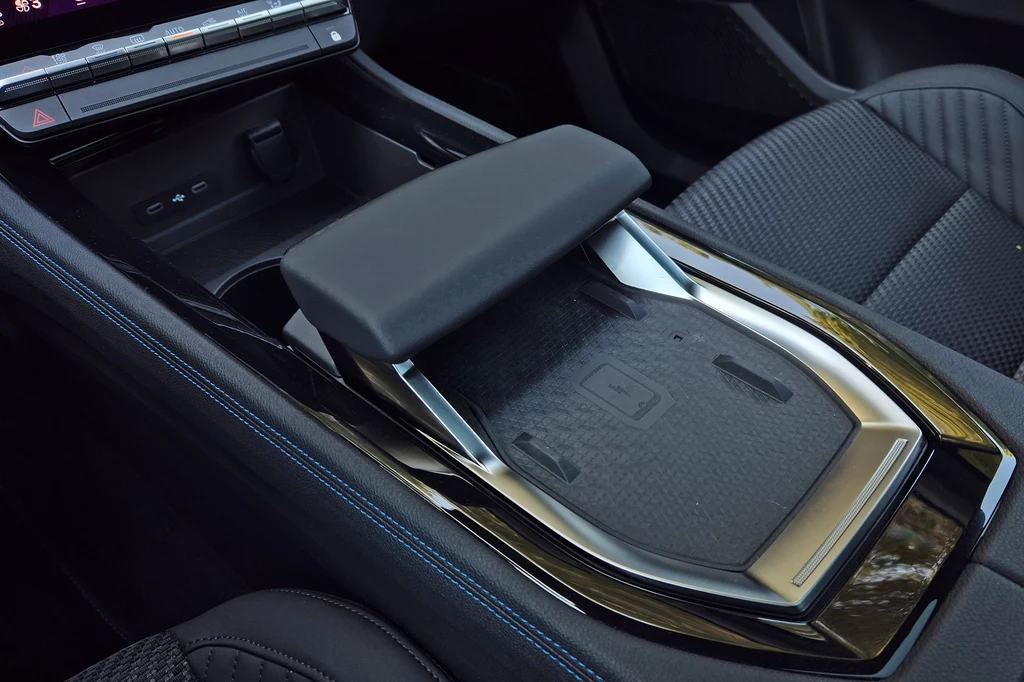 Renault Austral Konsola środkowa samochodu z nowoczesnym, designerskim podłokietnikiem, matą do ładowania indukcyjnego oraz elementami tapicerki foteli.