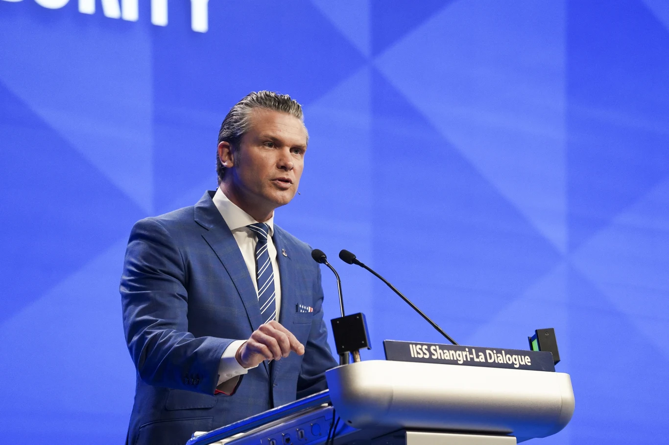 Chiny zareagowały na słowa sekretarza obrony USA Pete'a Hegsetha Mężczyzna w garniturze przemawia przy mównicy z mikrofonami podczas międzynarodowej konferencji IISS Shangri-La Dialogue na tle niebieskiego ekranu.
