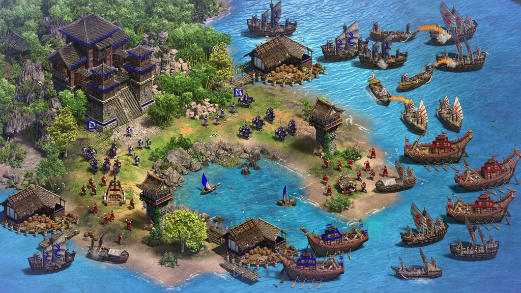 Age of Empires II: Definitive Edition Bitwa morska pomiędzy dwiema flotami w stylu średniowiecznym przy wyspie, na której widać fortyfikacje, budynki oraz żołnierzy rozmieszczonych w różnych częściach lądu.