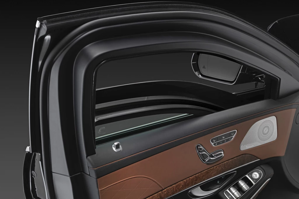 Mercedes S 600 Guard wyposażony jest w pancerne szyby Wnętrze luksusowego samochodu z widocznymi brązowo-czarnymi wykończeniami drzwi, panelami sterowania oraz lusterkiem bocznym.