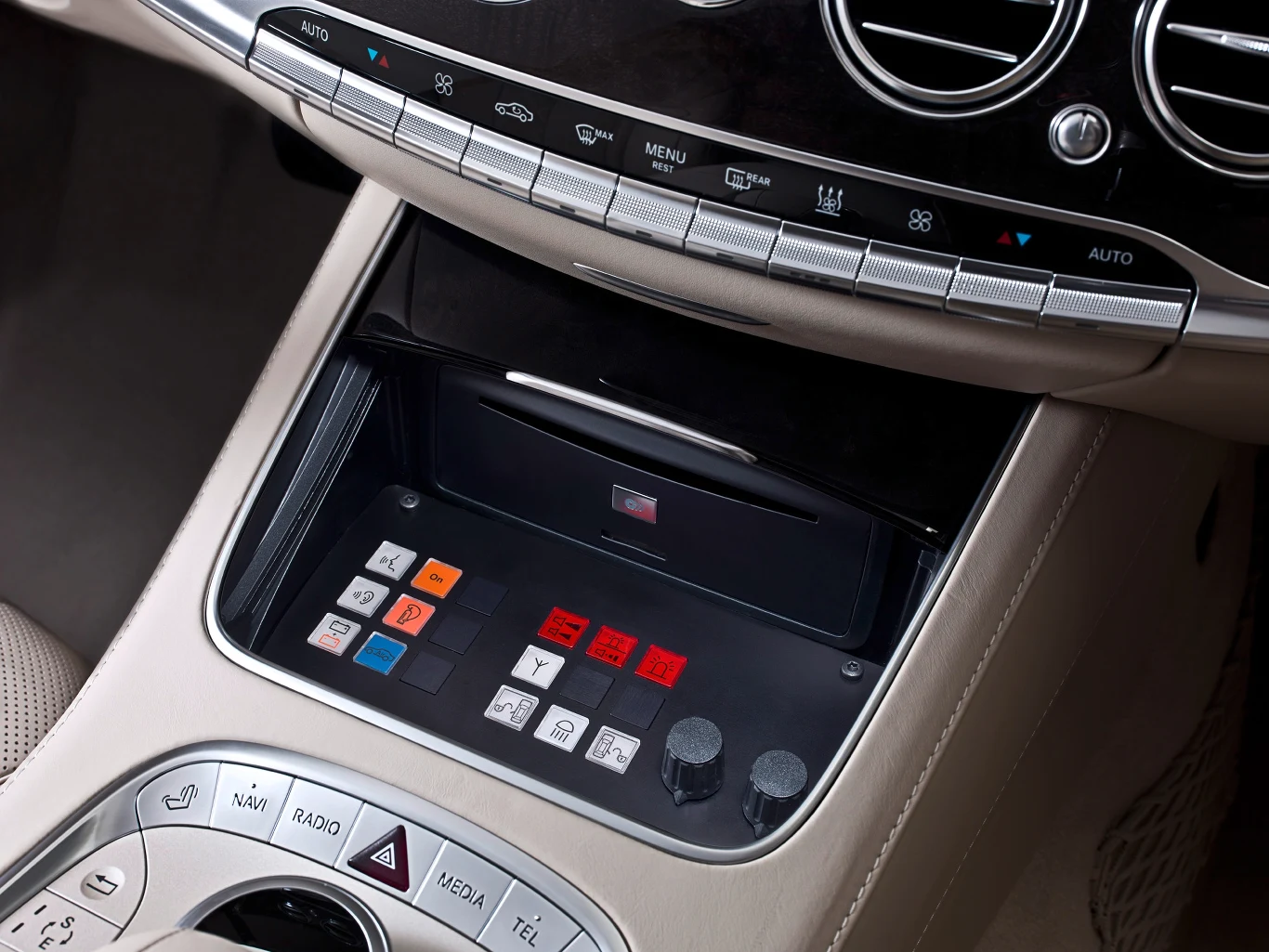 Panel sterowania z licznymi kolorowymi przyciskami i pokrętłami osadzony w konsoli środkowej luksusowego samochodu, otoczony elementami sterującymi klimatyzacją oraz radiem, wykonany z wysokiej jakości materiałów.