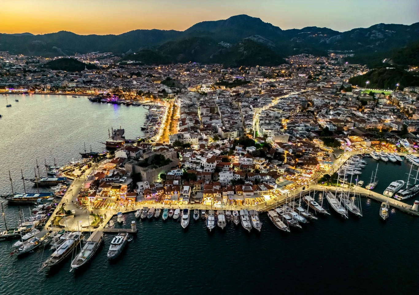 Trzęsienie ziemi w Turcji. Wstrząsy były odczuwalne m.in. w znanym kurorcie Marmaris. Zdjęcie ilustracyjne Panorama portowego miasta o zmroku, z licznymi jachtami zacumowanymi wzdłuż nabrzeża, rozświetlonymi ulicami oraz górzystym krajobrazem w tle.
