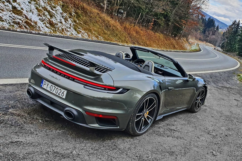 Wśród najdroższych samochodów polskich posłów znalazło się m.in. Porsche 911 Turbo. Sportowy kabriolet Porsche 911 Turbo S zatrzymany na poboczu asfaltowej, krętej drogi w górskim otoczeniu z lekko ośnieżonymi wzgórzami w tle.
