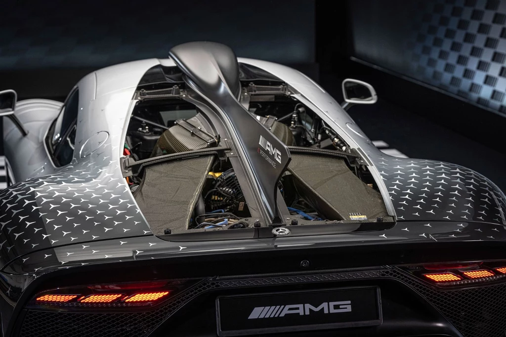 Hybrydowy układ napędowy Mercedesa-AMG One generuje 1043 KM Nowoczesny supersamochód z widocznym silnikiem V6, zaawansowaną aerodynamiką oraz wyraźnym logo AMG, efektowne tylne światła LED i sportowy charakter karoserii.