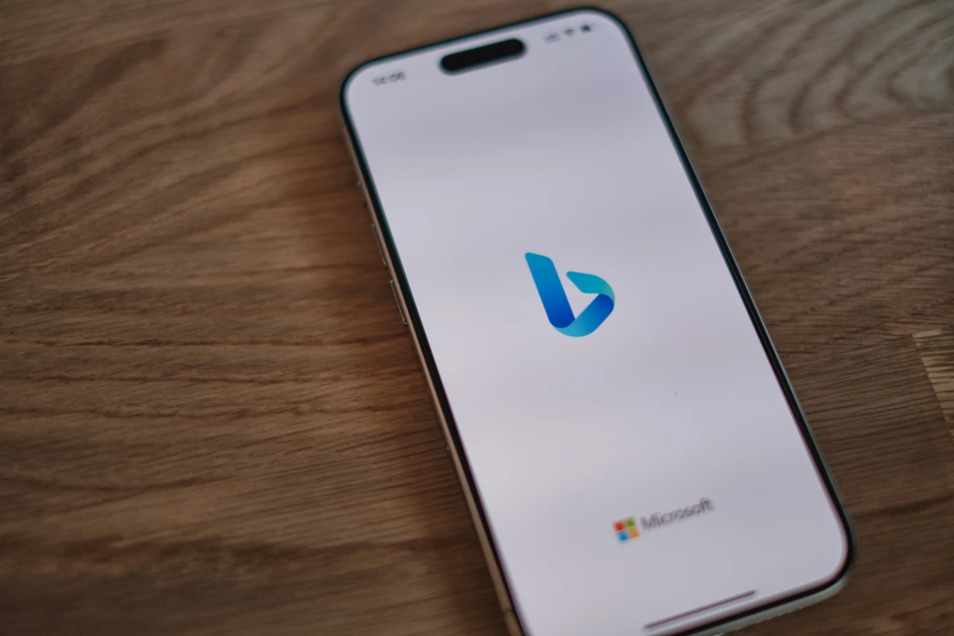 Generator wideo Sora za darmo w Bing. Microsoft rusza z nowym narzędziem AI Smartfon z widocznym logo Bing na ekranie, w dolnej części ekranu widoczne logo Microsoftu, urządzenie leży na drewnianej powierzchni.