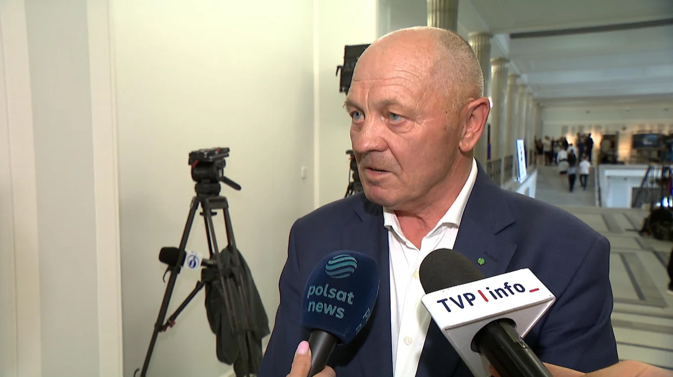 Marek Sawicki ma kontrpropozycję dla Donalda Tuska Starszy mężczyzna w garniturze udziela wywiadu dwóm stacjom telewizyjnym, w tle statyw z kamerą oraz jasne wnętrze budynku.