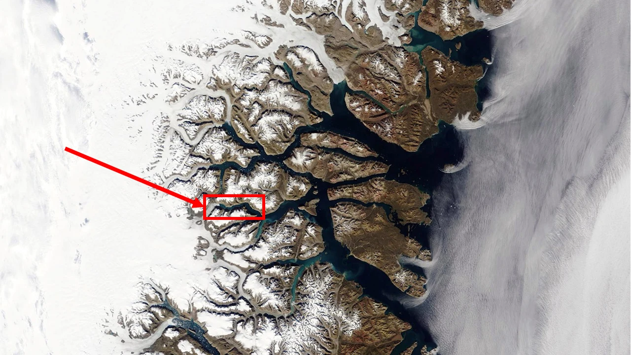 Naukowcy odkryli źródło drgań Ziemi z 2023 r. To były fale z Grenlandii. Na zdjęciu Dicksons Fjord na Grenlandii Obszar arktyczny z licznymi fiordami i lodowcami, pokryty śniegiem i lodem, zaznaczony czerwonym prostokątem oraz strzałką wskazującą konkretny punkt na mapie.