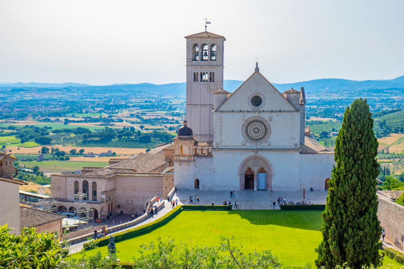 Co roku do Asyżu przybywa wielu pielgrzymów. Przez najbliższy miesiąc będą to jednak prawdziwe tłumy Historyczna bazylika z jasnego kamienia z charakterystyczną wieżą i rozetą, otoczona zielonym trawnikiem i cypressami, w tle rozciąga się malownicza panorama pól i pagórków.