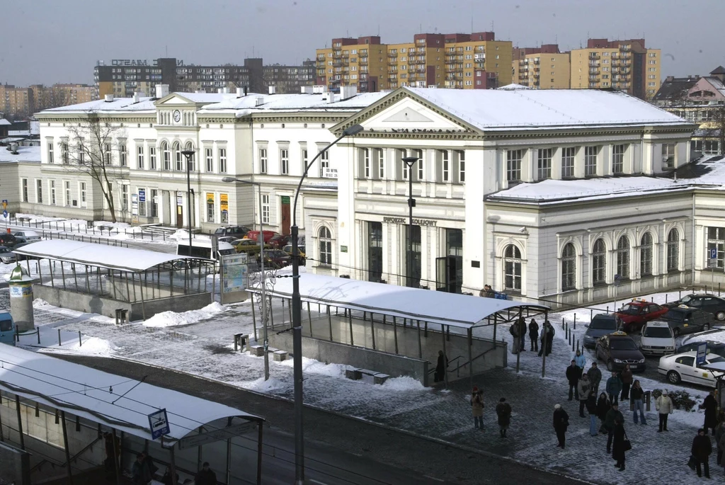 Sosnowiec został uznany za najbrzydsze polskie miasto według AI, czy słusznie? Historyczny budynek dworca kolejowego na tle zimowego miasta, z przykrytymi śniegiem dachami, otoczony przez przechodniów, samochody oraz bloki mieszkalne w tle.