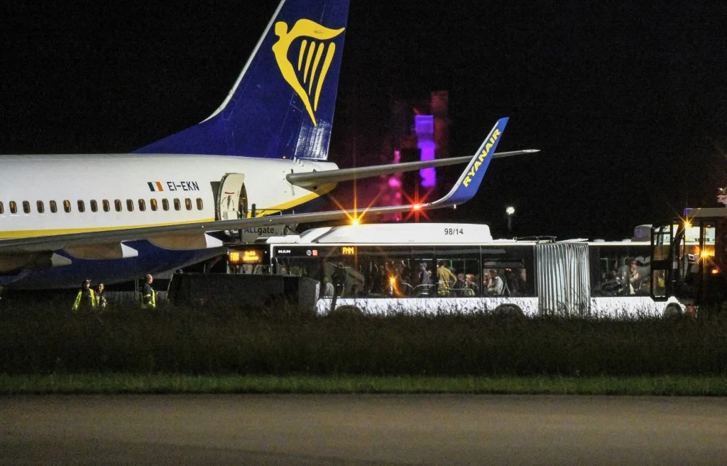 Niemcy. Potężne turbulencje zmusiły pilota do awaryjnego lądowania. Są poszkodowani Samolot linii Ryanair stojący na płycie lotniska w nocy, obok samolotu autobus lotniskowy z pasażerami przemieszczającymi się między pojazdami a maszyną, w tle widoczne oświetlenie lotniskowe.