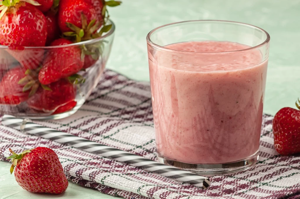 Strawberry smoothie with milk in a glass on a green background, healthy eating for breakfast and snacks