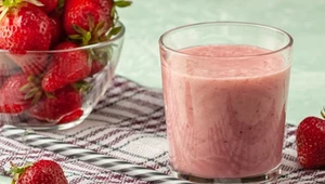 Strawberry smoothie with milk in a glass on a green background, healthy eating for breakfast and snacks