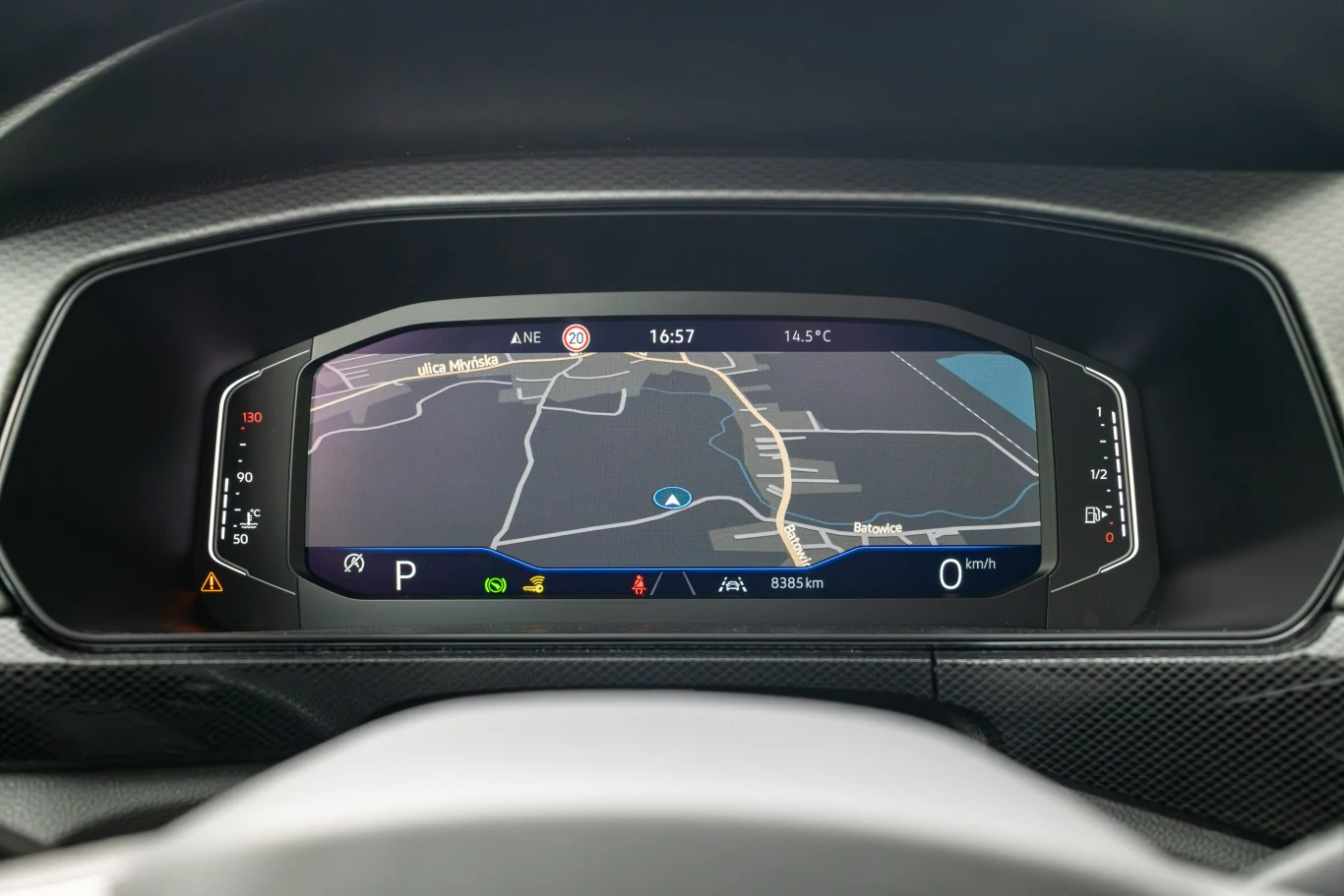 Cyfrowy kokpit samochodu z wyświetlaczem prezentującym mapę nawigacji GPS, wybrane parametry jazdy oraz wskaźniki dotyczące prędkości i poziomu paliwa.