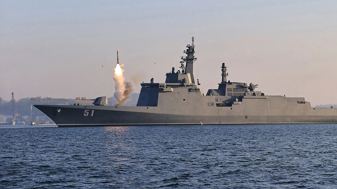 Przewrócona fregata klasy Choi Hyon marynarki Korei Północnej została podniesiona. Jednak do uratowania daleko Rosyjski okręt wojenny wypuszcza rakietę nad powierzchnią morza, widoczny dym i ogień z wystrzału, w tle zarys linii brzegowej.