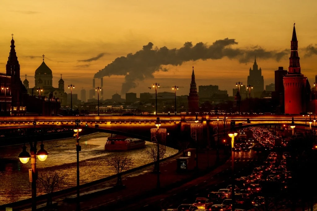 Ukraina zaatakowała w obwodzie moskiewskim (zdjęcie ilustracyjne) Panorama miasta o zmierzchu z dominującym widokiem na kremlowskie wieże, most, rzekę oraz długą kolejkę samochodów, a w tle unoszący się dym z kominów zakładów przemysłowych.