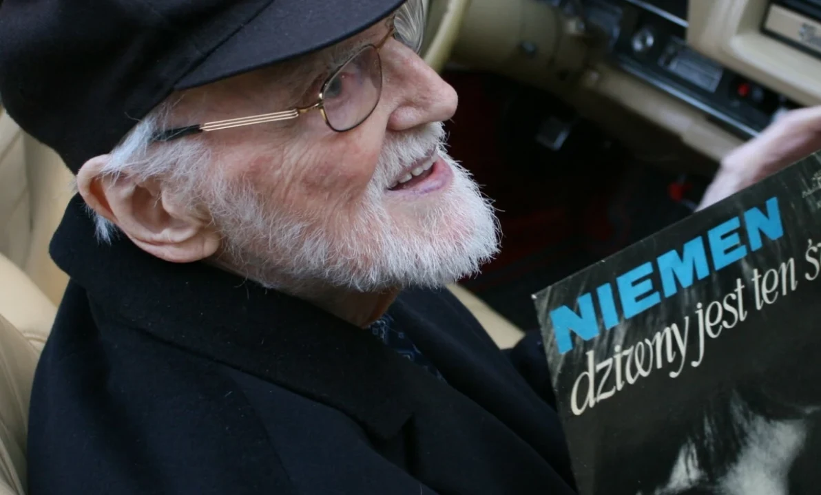 Franciszek Walicki nazywany był "ojcem chrzestnym polskiego rock'n'rolla" Starszy mężczyzna z siwą brodą i okularami, uśmiechnięty, siedzi w jasnym wnętrzu samochodu, trzymając w dłoniach płytę winylową z widocznym napisem NIEMEN dżwony jest ten świat.