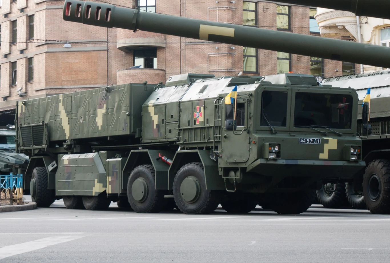 Grom-2, czyli ukraińska odpowiedź na Iskandery i KN-23, podczas parady w 2018 roku Wojskowy pojazd transportowy z systemem rakietowym ustawiony na miejskiej ulicy, otoczony zabudowaniami z cegły i elementami nowoczesnej architektury.