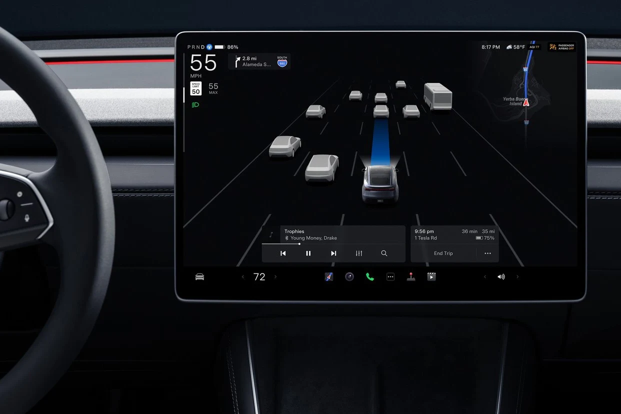 Ekran dotykowy w samochodzie pokazujący interfejs autopilota z widokiem aktualnych pojazdów na drodze, wskazaniem pasa oraz szczegółami dotyczącymi prędkości, muzyki i trasy przejazdu.