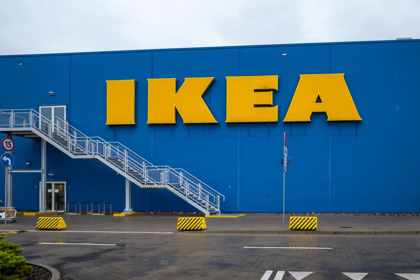 Fabryka Ikea zwalnia. To już 300 osób w 2024 roku Duży niebieski budynek sklepu IKEA z charakterystycznym żółtym logo, zewnętrznymi schodami ewakuacyjnymi i pustym parkingiem na pierwszym planie.