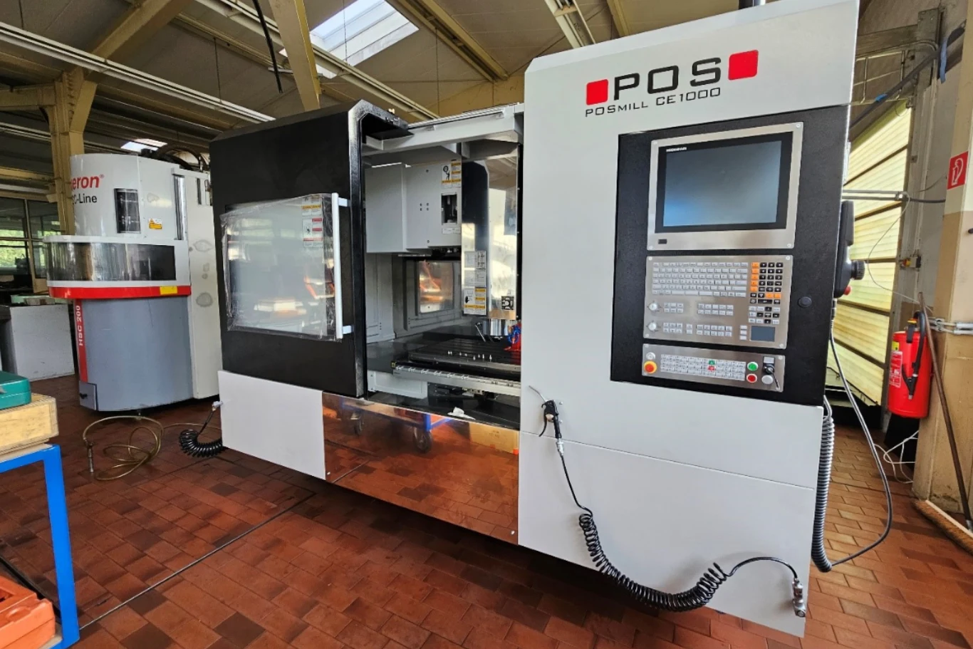 Centrum frezarskie POSMILL CC 1000 wyposażone w panel sterowania komputerowego, otwartą komorę roboczą oraz wyraźnie widoczne elementy konstrukcji przemysłowej w hali produkcyjnej.