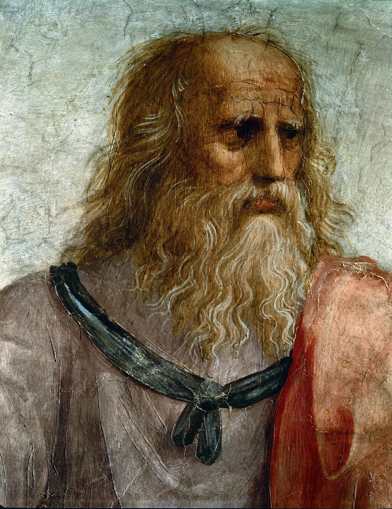 Kim są potomkowie da Vinci? Starzec o długiej, siwej brodzie i długich włosach, ubrany w jasną tunikę i czerwoną szatę, spoglądający zamyślonym wzrokiem; tło w odcieniach szarości i beżu, brak dodatkowych, rozpraszających elementów