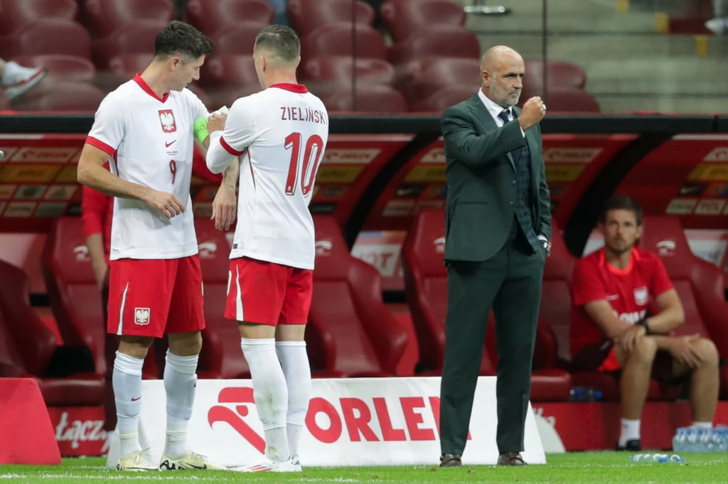 Piotr Zieliński zakłada opaskę kapitana Robertowi Lewandowskiemu. Z boku trener Michał Probierz